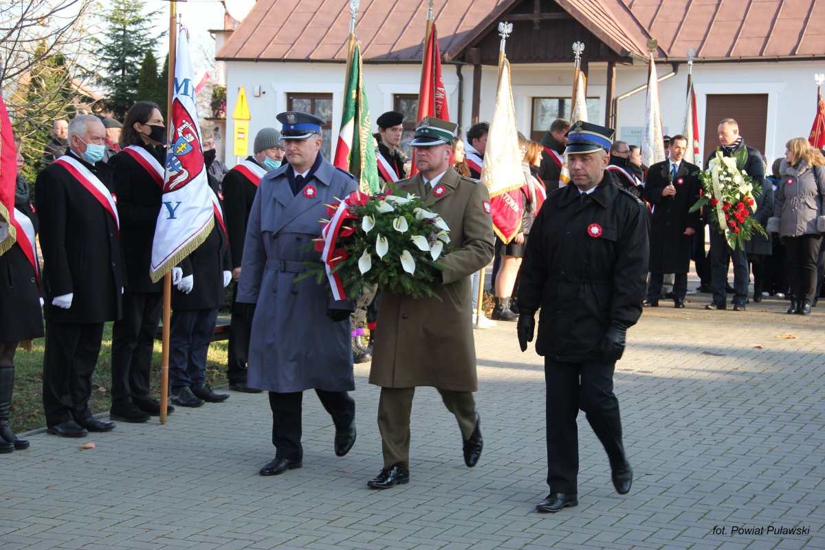 przedstawiciele służb mundurowych maszerujący z wieńcem biało czerwonym