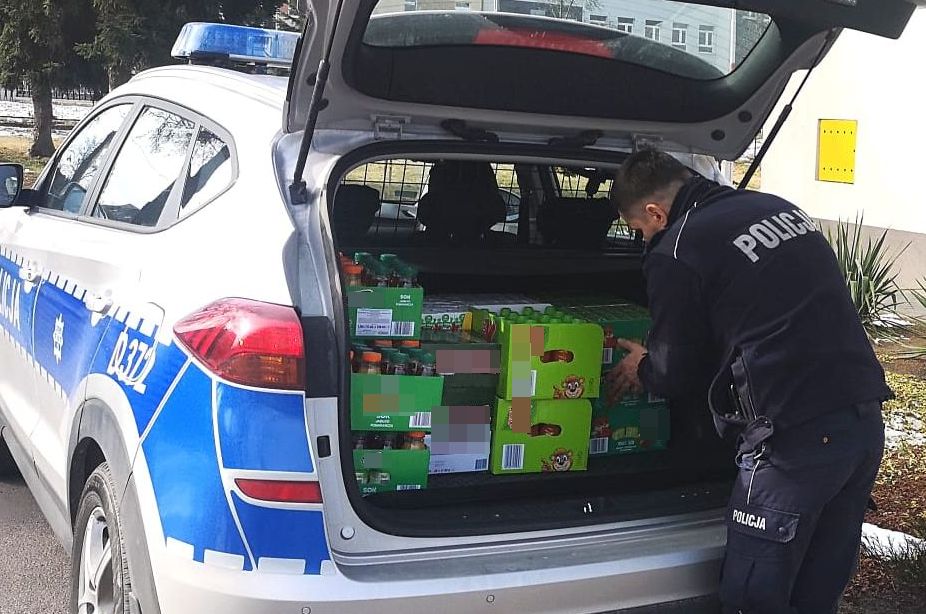policjant ładujący pudła ze słodyczami do bagażnika radiowozu