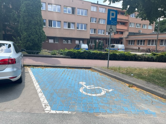 miejsce parkingowe dla osób niepełnosprawnych przy ulicy Wojska Polskiego w Puławach. W drugim planie widzimy budynek Komendy Powiatowej Policji w Puławach 