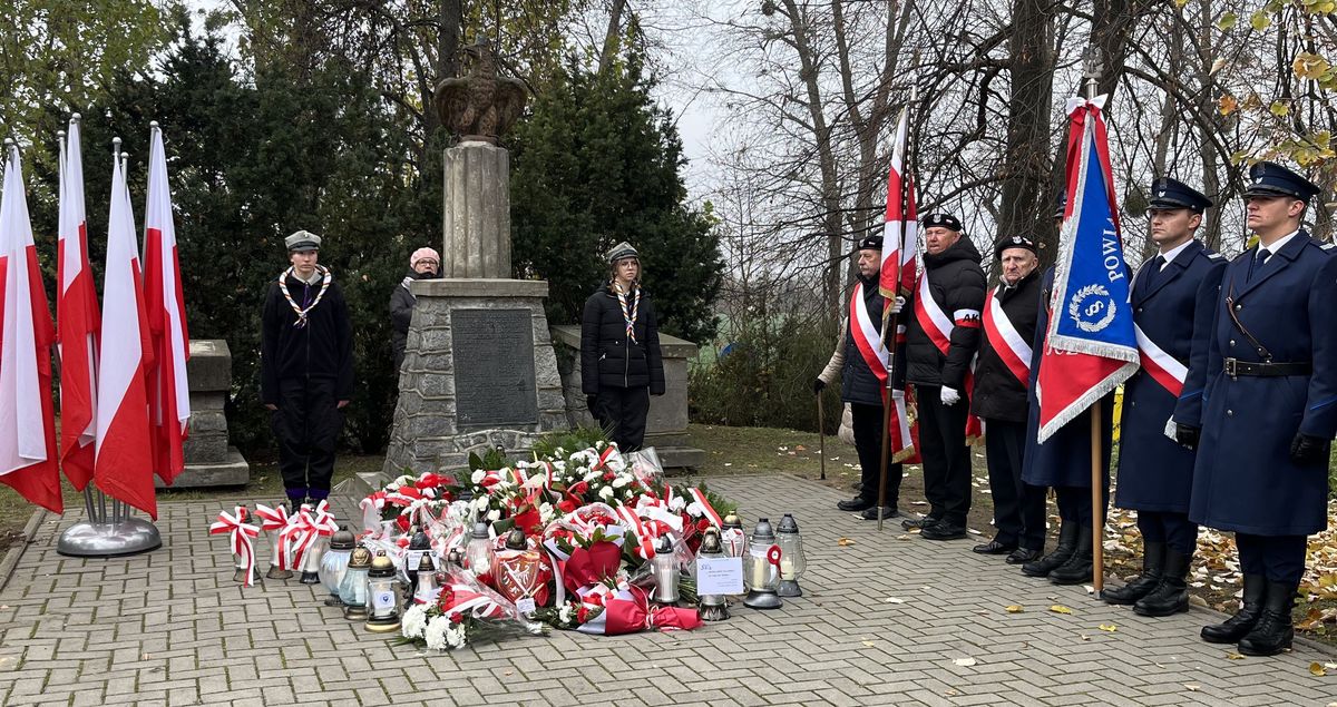 pomnik pod nim wiązanki obok poczty sztandarowe