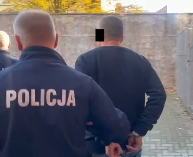 policjant w mundurze prowadzi zatrzymanego