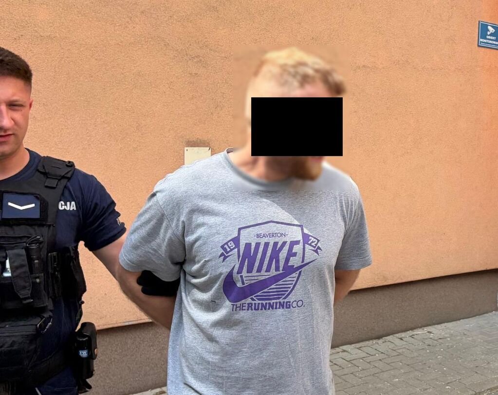 Policjant prowadzi zatrzymanego mężczyznę.