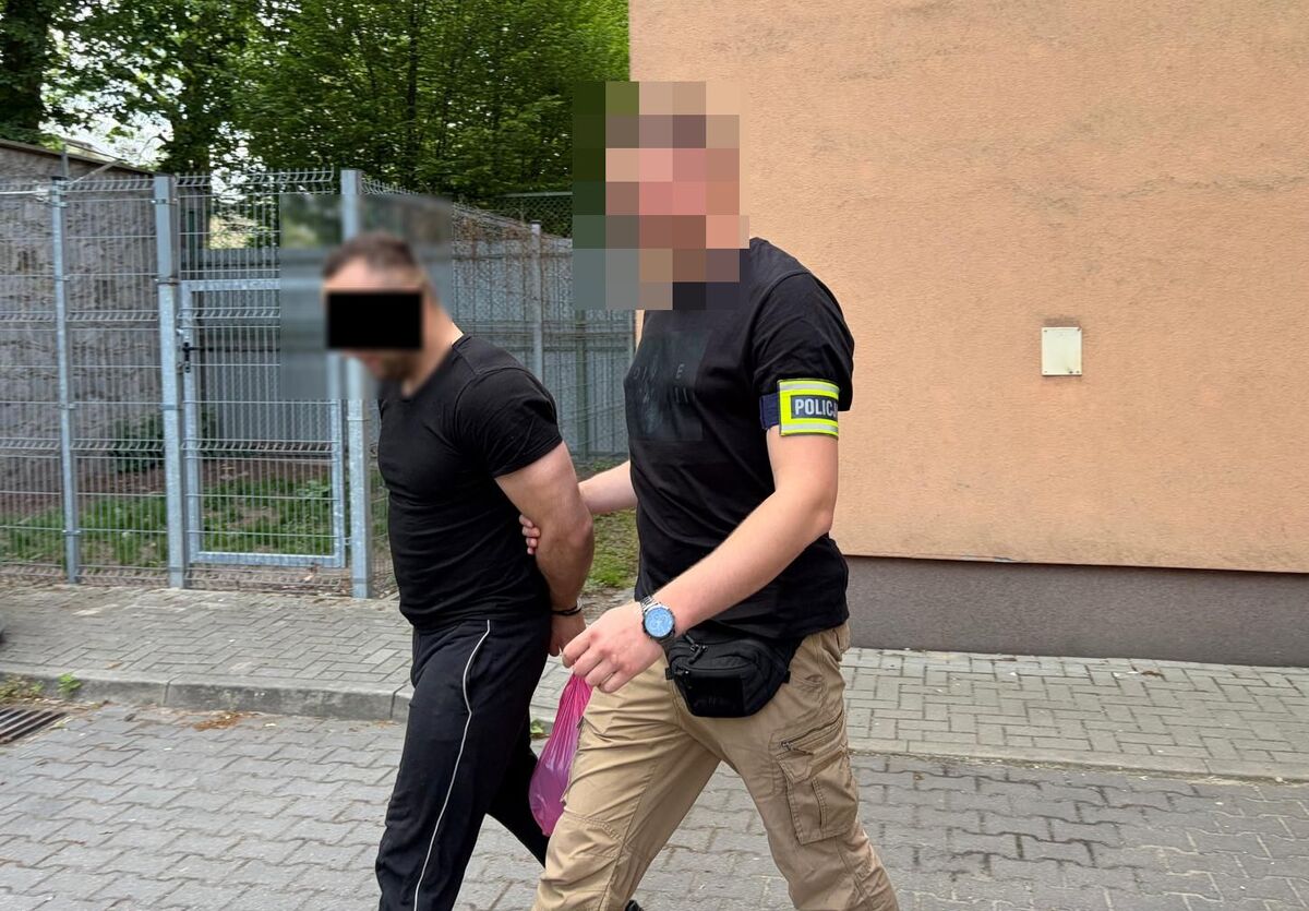 Policjant prowadzi zatrzymanego mężczyznę.