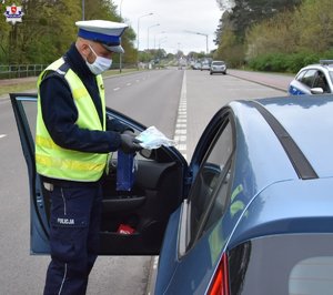 policjant RD przekazujący kierowcy maseczkę