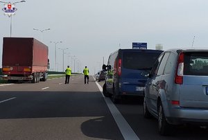 ford, ciążarówka i policyjny bus stojący na drodze, w tle dwóch policjantów