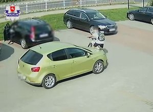 żółty seat na parkingu przed nim rowerzysta na rowerze wokół inne zaparkowane samochody