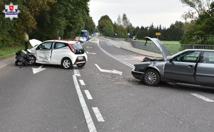 miejsce wypadku na drodze rozbite samochody szare audi i biała toyota, policjant nachylony przy toyocie