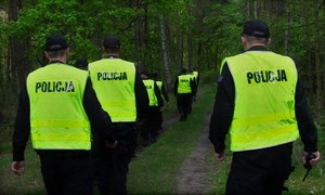 policjanci idący nocą przez las