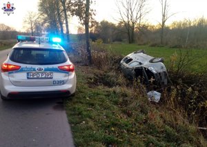 samochód leżący na boku w rowie obok na ulicy stoi policyjny radiowóz