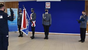 policjant ślubujący na sztandar powtarzający rotę ślubowania czytaną przez komendanta