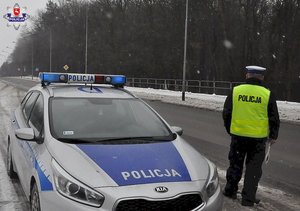 policjant stojący przy drodze obok radiowozu