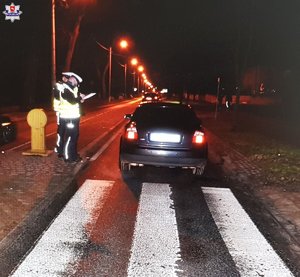 czarne audi stojące za przejściem dla pieszych dwóch policjantów prowadzących oględziny