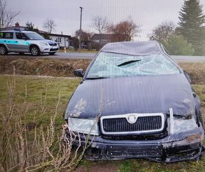 czarna rozbita skoda w rowie, w tle na szosie radiowóz