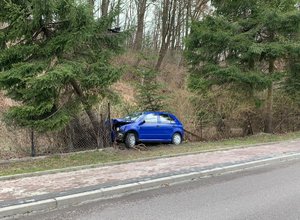 niebieska skoda rozbita na ogrodzeniu przy drodze