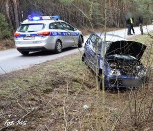 niebieski fiat seicento w rowie, obok na szosie radiowóz