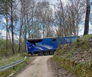 niebieska naczepa ciężarówki zablokowana na drodze polnej