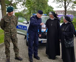 policjant i żołnierz z dwiema siostrami zakonnymi w tle radiowóz