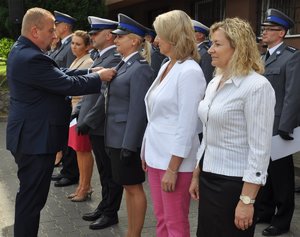 mężczyzna przypinający odznaczenie policjantce