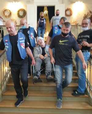 czterech mężczyzn znoszących po schodach mężczyznę na wózku inwalidzkim