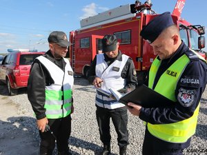 policjant i strażacy obok wozu strażackiego