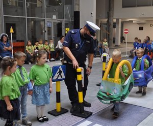 policjant z dziećmi w miasteczku ruchu drogowego