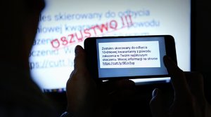 na pierwszym planie telefon komórkowy z treścią fałszywej wiadomości od oszustów o 10 dniowej kwarantannie