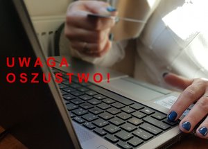 napis uwaga oszustwo na tle dłoni przy klawiaturze komputera