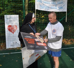 zastępca komendanta policji wręczający czek siostrze zakonnej