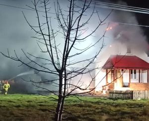 palący się dom  gaszący go strażacy