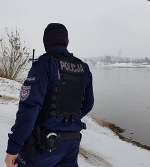 policjant na ośnieżonym brzegu rzeki