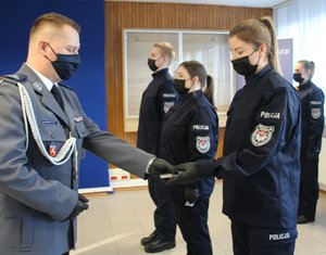 komendant podający legitymację policjantce w tle inni policjanci