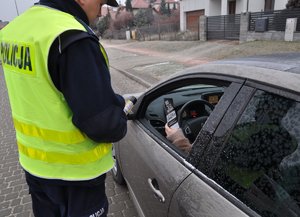 policjant stoi obok samochodu kierowca trzyma w ręce ulotkę