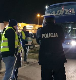 policjant stojący tyłem na wprost autobusu obok niego dwóch mężczyzn