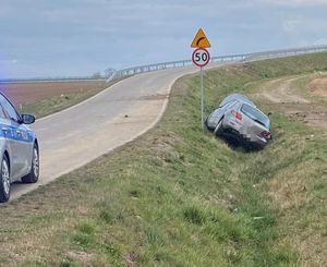 szary samochód leżący w rowie na ulicy radiowóz