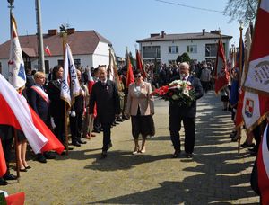 starlsta z członkami zarządu niosą wieniec białoczerwony