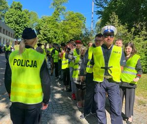 policjanci z grupą młodzieży w kamizelkach odblaskowych