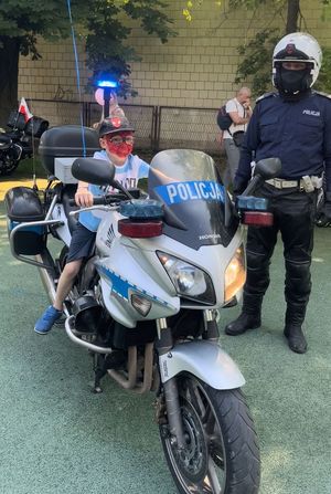 dziecko na motocyklu policyjnym obok policjant