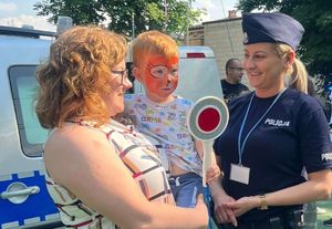 policjantka stojąca z matką trzymającą na rękach dziecko zajawka