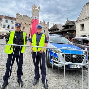 dwóch policjantów stoi na rynku w tle radiowóz i figura króla
