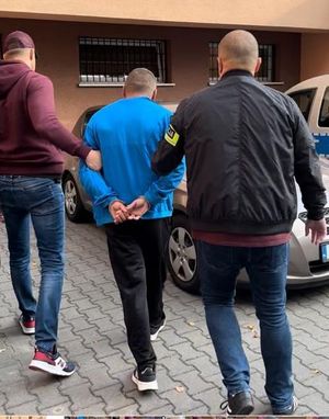 policjanci po cywilnemu prowadzą zatrzymanego w kajdankach