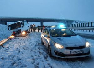 radiowóz na zaśnieżonej drodze  w tle cysterna w rowie