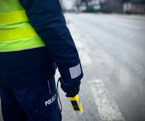 policjant przy drodze z urządzeniem do badania na trzeźwość