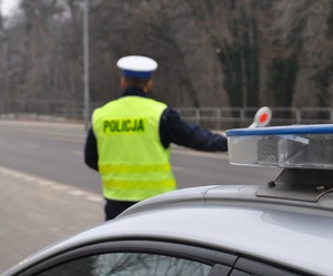 policjant z tarczą do zatrzymywania pojazdów stoi na drodze