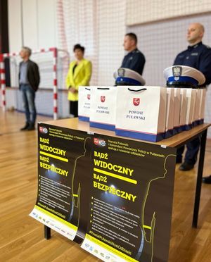 komisja konkursowa na tle plakatów i torebek prezentowych