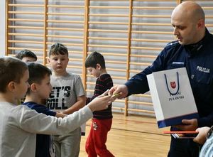 policjant dający chłopcu odblask