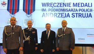 dwóch odznaczonych policjantów z ministrem spraw wewnętrznych i administracji oraz komendantem głównym policji