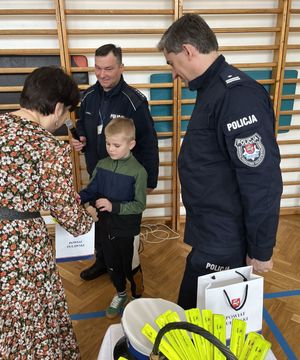 starosta i dwóch policjantów wręczający prezent dziecku
