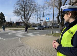 piesi przechodzący po przejściu patrzy na nich policjantka