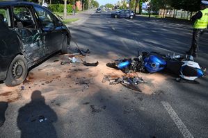 Miejsce wypadku na ulicy Lubelskiej w Puławach rozbity motocykl i uszkodzony samochód obok nich stoi policjant