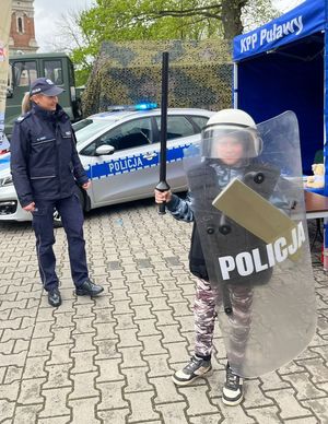 dziecko z tarczą i w hełmie policyjnym obok policjantka